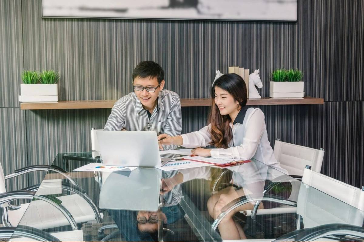 Two people sitting at a table with laptops