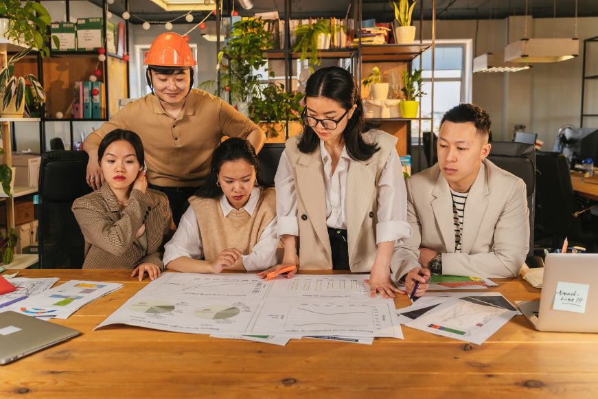 A group of people sitting around a table with papers.