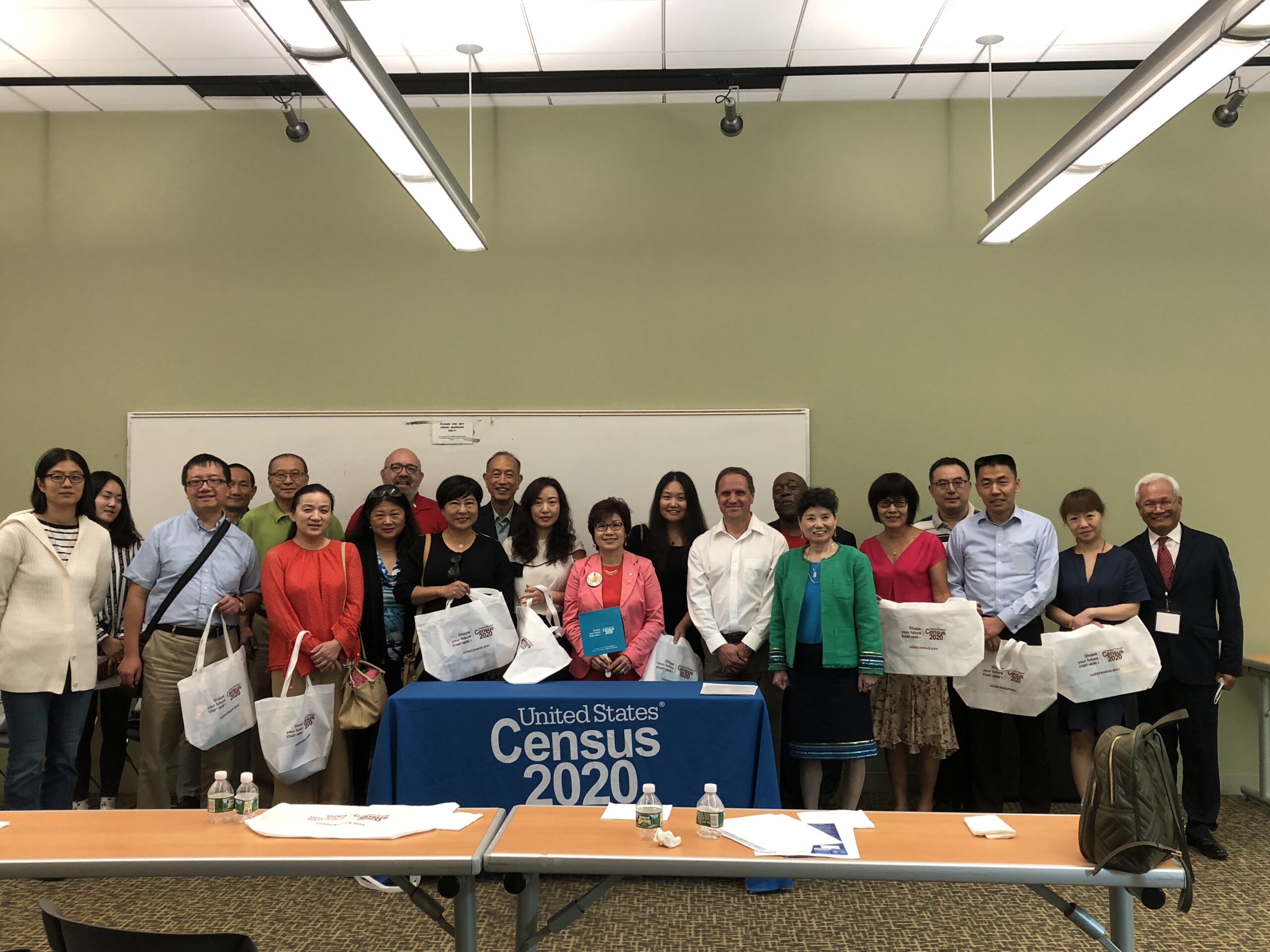 A group of people holding bags in front of a table.