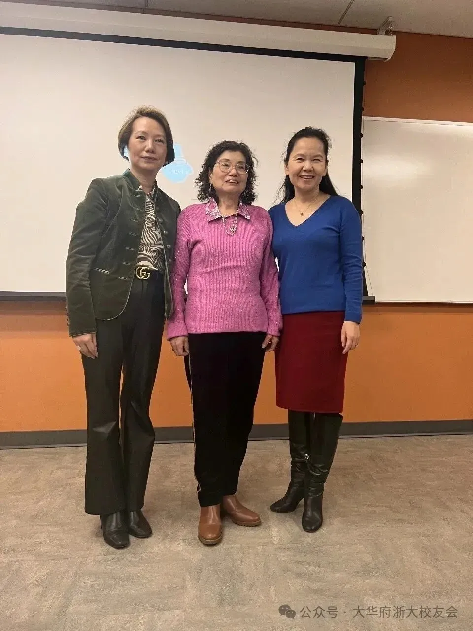 Three women posing before classroom projection screen