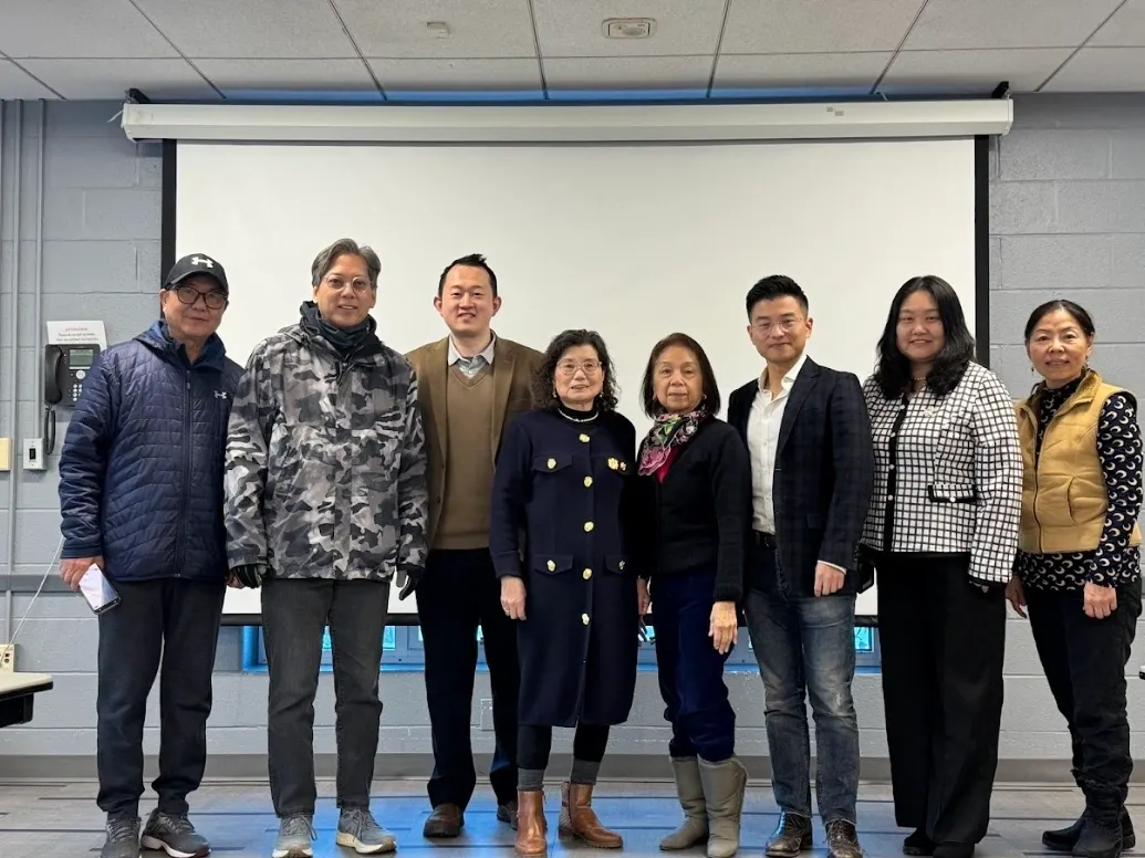 Eight adults posing before classroom projection screen